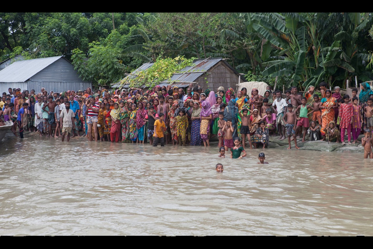 Жители деревни ждут лодку, чтобы спастись от наводнения в июле 2016 года в Ислампуре, Джамалпуре, Бангладеш. Бангладеш является одним из самых уязвимых мест в мире из-за повышения уровня моря, которое, как ожидается, к 2050 году приведет к тому, что десятки миллионов людей останутся без крова. Фото: Пробал Рашид