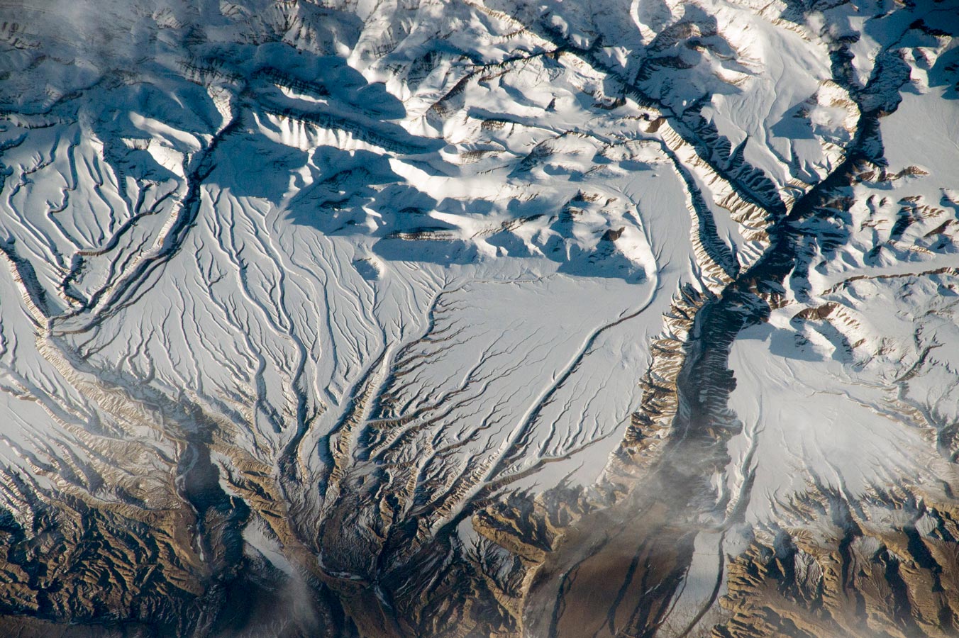 Реки и снега в Гималаях на границе Индии и Китая, где пики бросают вечерние тени на снегу.