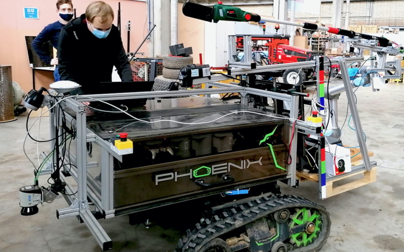 Робот Phoenix с установленной на руке механической электропилой в ножнах (зеленого цвета) виден вверху фотографии.