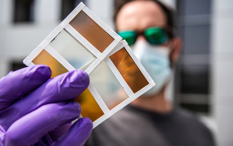 Исследователь Лэнс Уиллер держит образцы новых термохромных фотоэлектрических окон, которые могут переключать цвета в ответ на тепло и генерировать электричество из солнечного света.