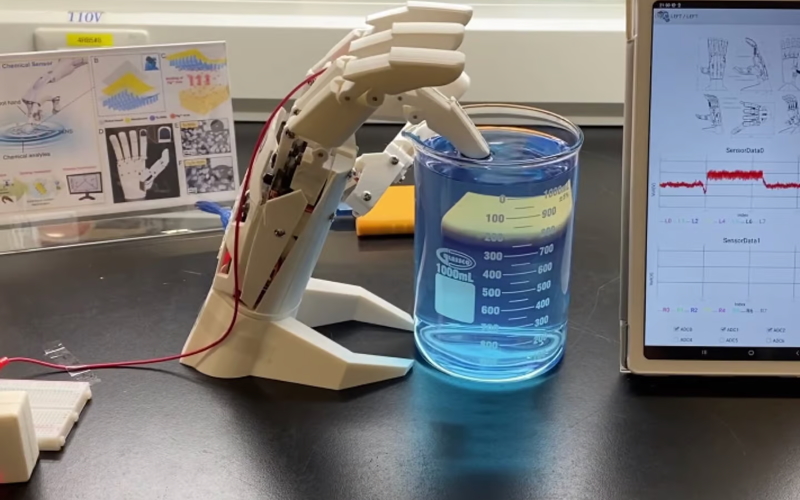 Трибоэлектрический наносенсор, прикрепленный к подушечке пальца роботизированной руки, проверяет образец в виде жидкости на загрязнение ртутью.