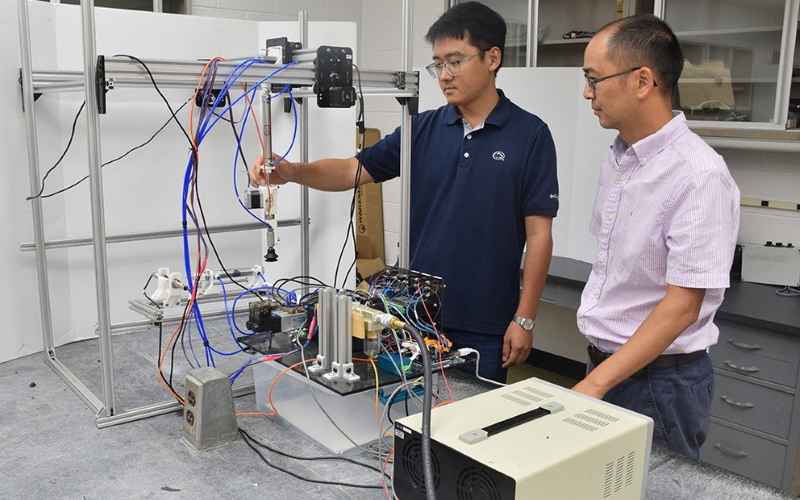Доцент Лонг Хе (справа) и приглашенный докторант Мингсен Хуанг с прототипом робота.